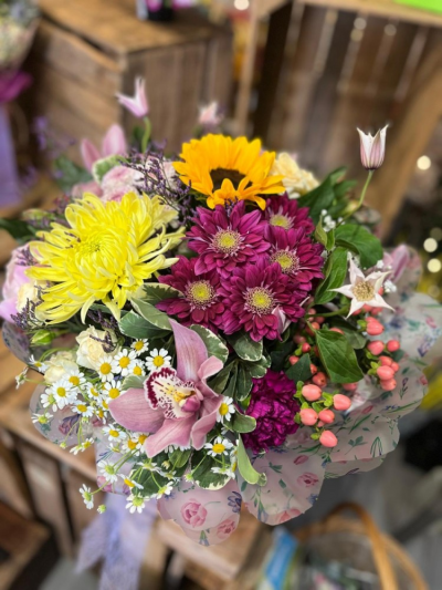 Sunshine Symphony - A beautifully handcrafted hand-tied bouquet presented in water, featuring a vibrant mix of seasonal blooms.